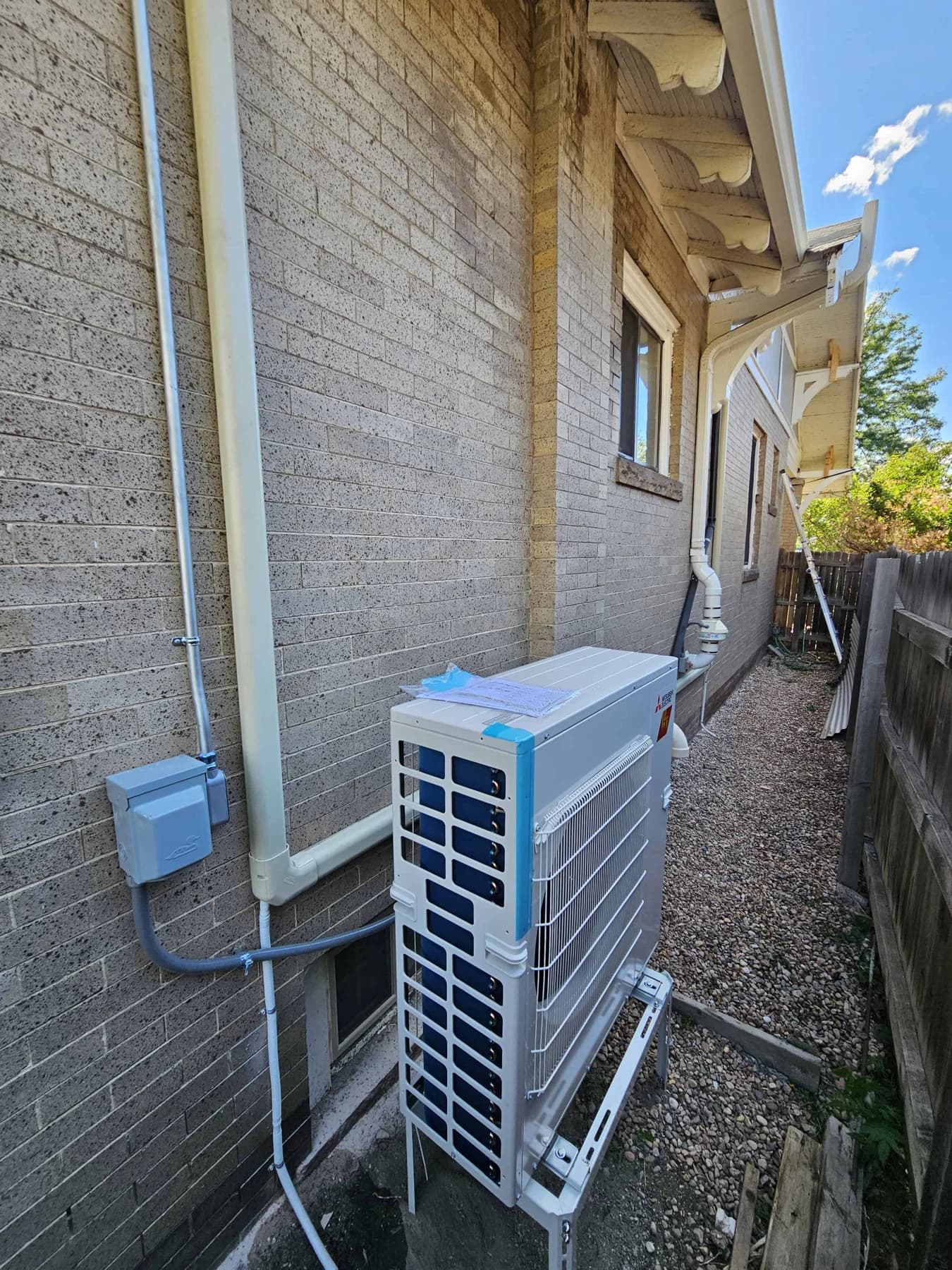 Outdoor heat pump, disconnect, and line route in a narrow gravel side yard